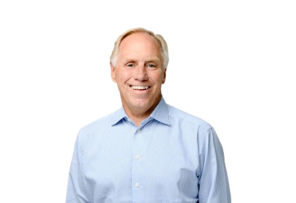 A smiling older man with short light hair wearing a light blue button-up shirt, standing against a transparent background.